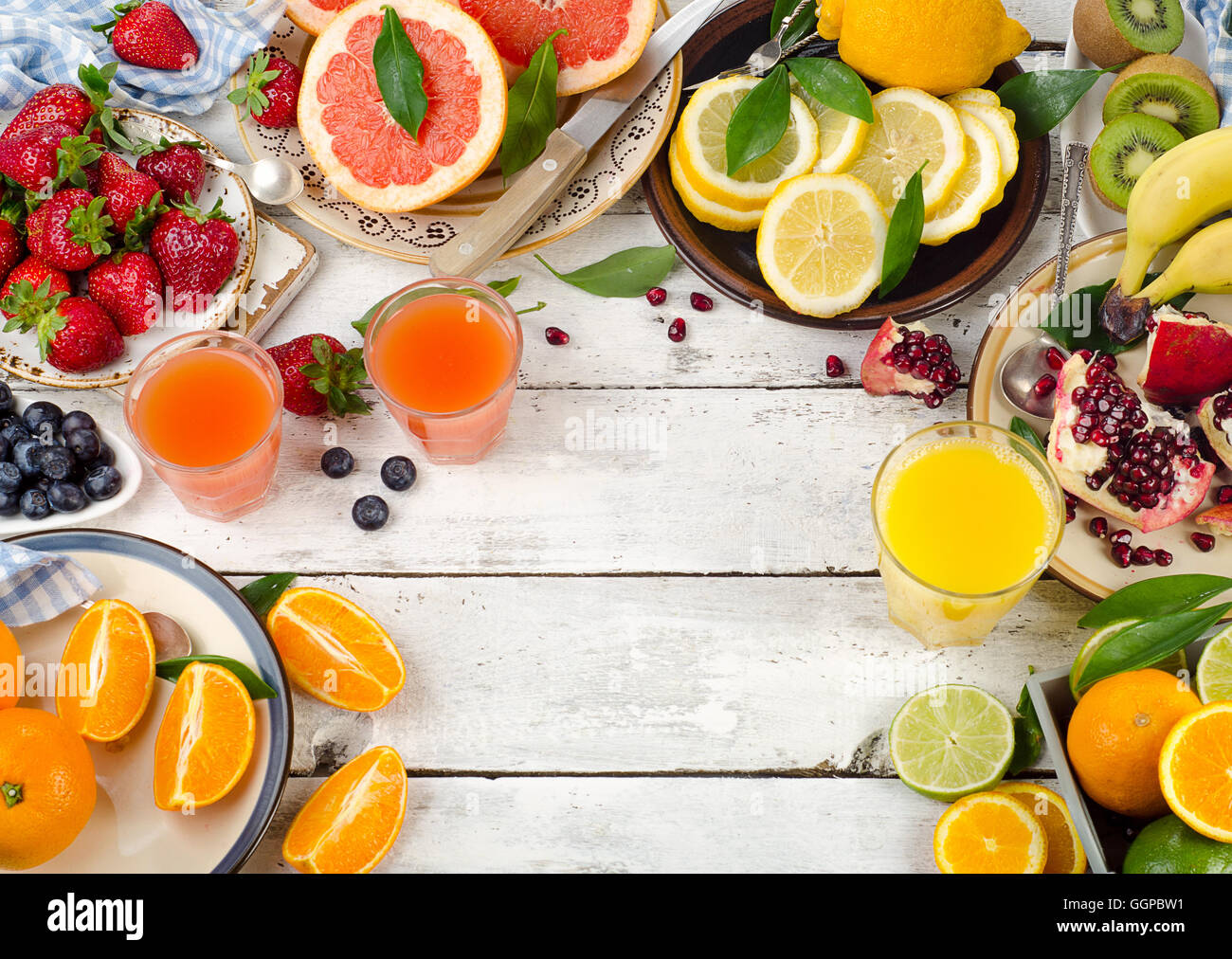 Citrus juice, fresh fruits and berries on white wooden background. Healthy eating, dieting. Top view Stock Photo