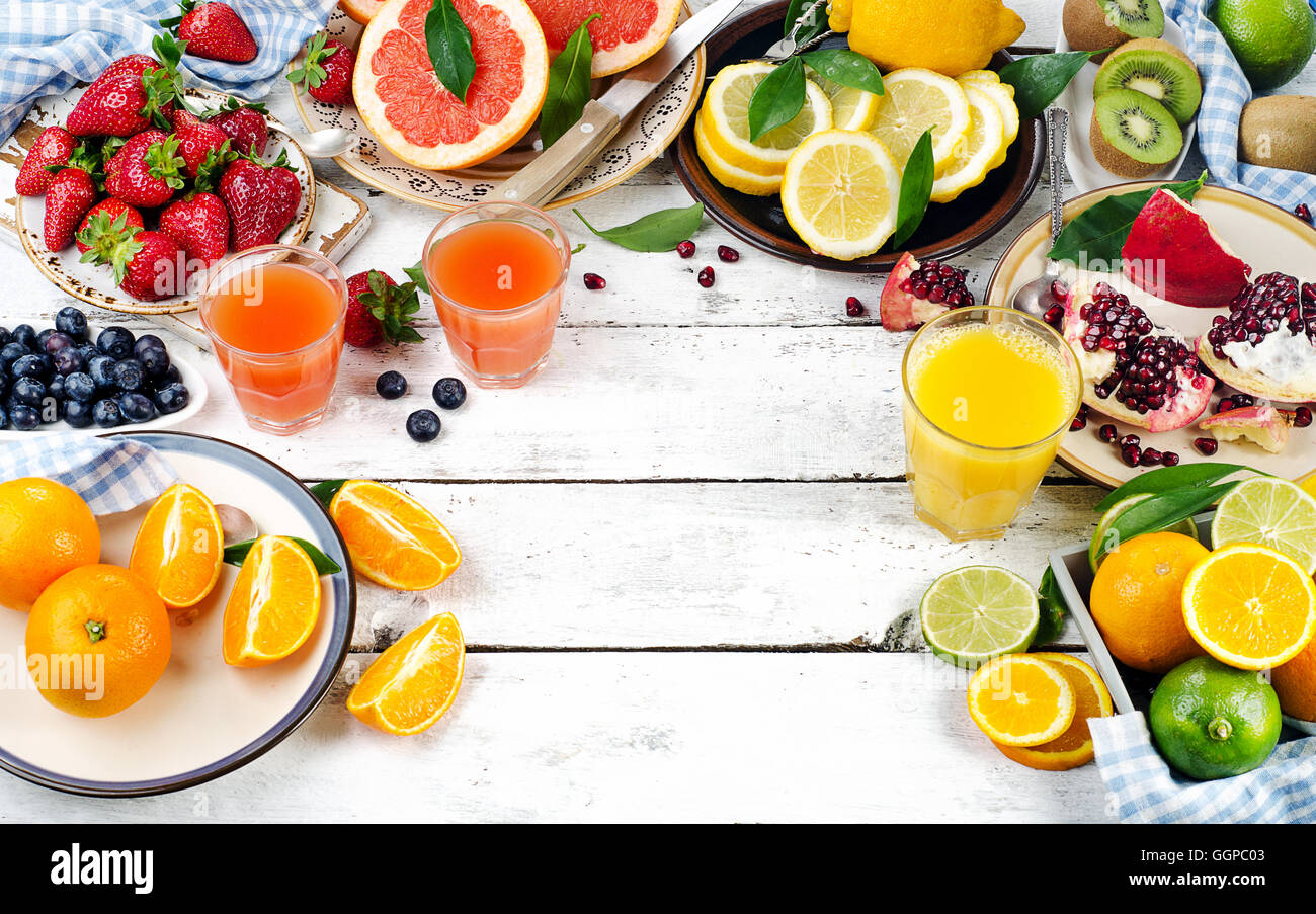 Citrus juice, fresh fruits and berries on a white wooden background. Healthy eating, dieting. Top view Stock Photo