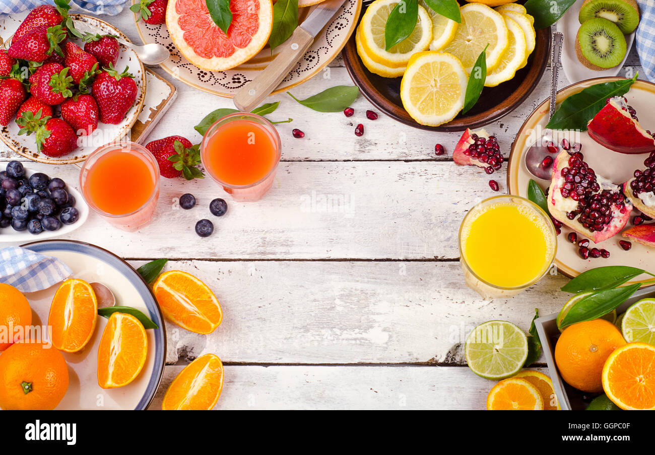 Citrus juice, fresh fruits and berries on white wooden background. Healthy eating, dieting. Top view Stock Photo