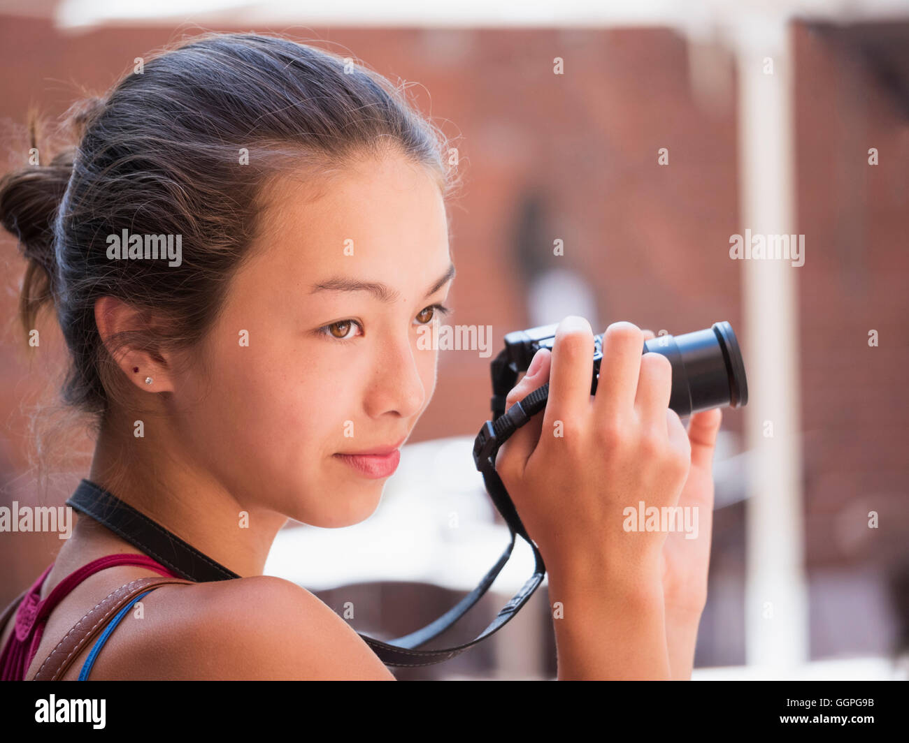 Mixed Race girl photographing outdoors with digital camera Stock Photo