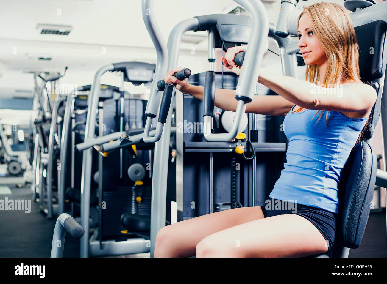 Woman using weight machines in gym Stock Photo Alamy