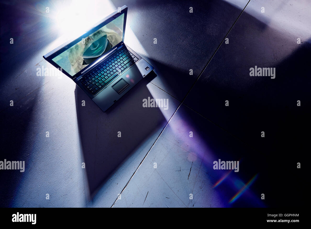 Face of hacker glowing on screen of laptop computer Stock Photo