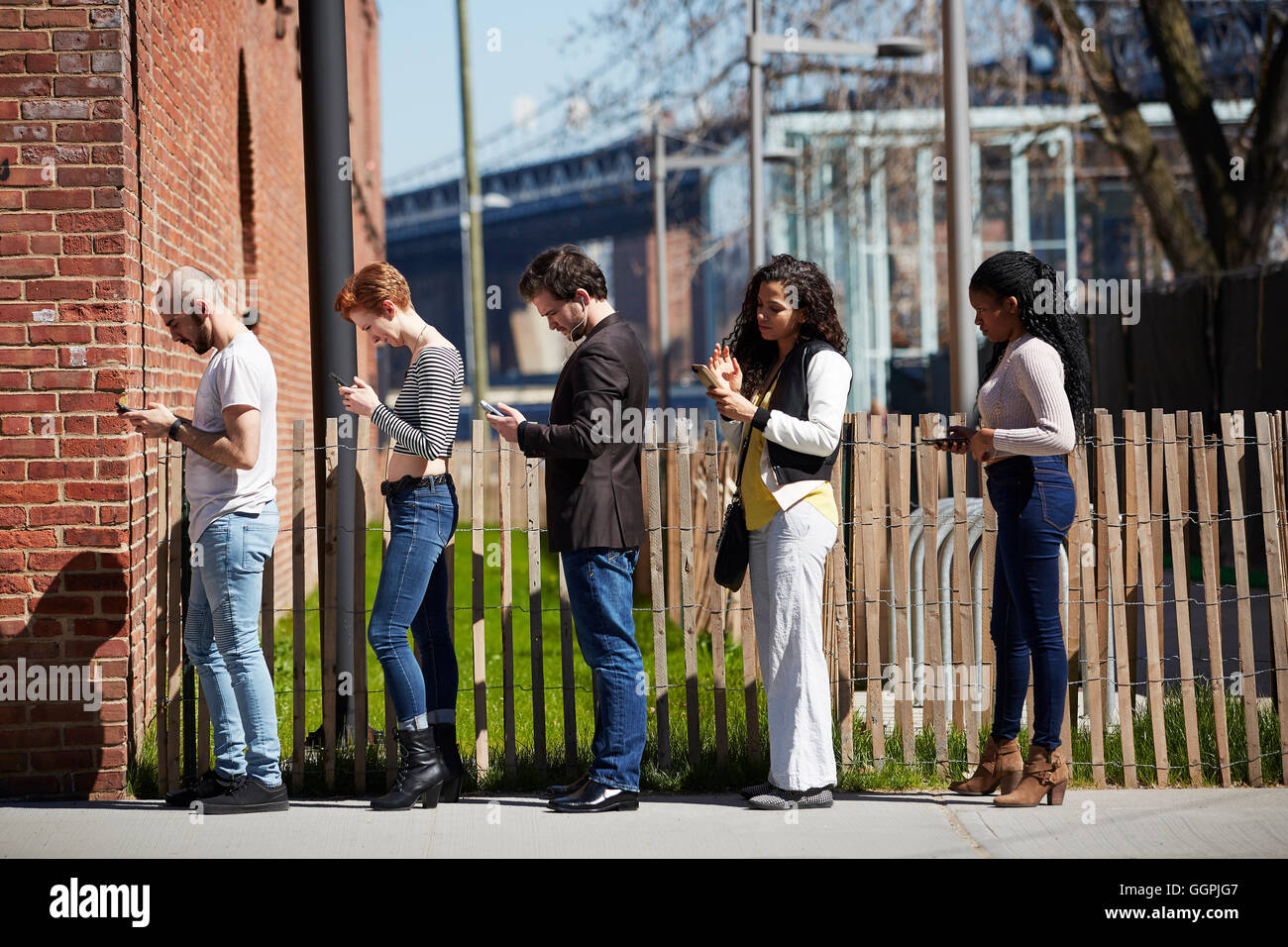 People in line on sidewalk using cell phones Stock Photo