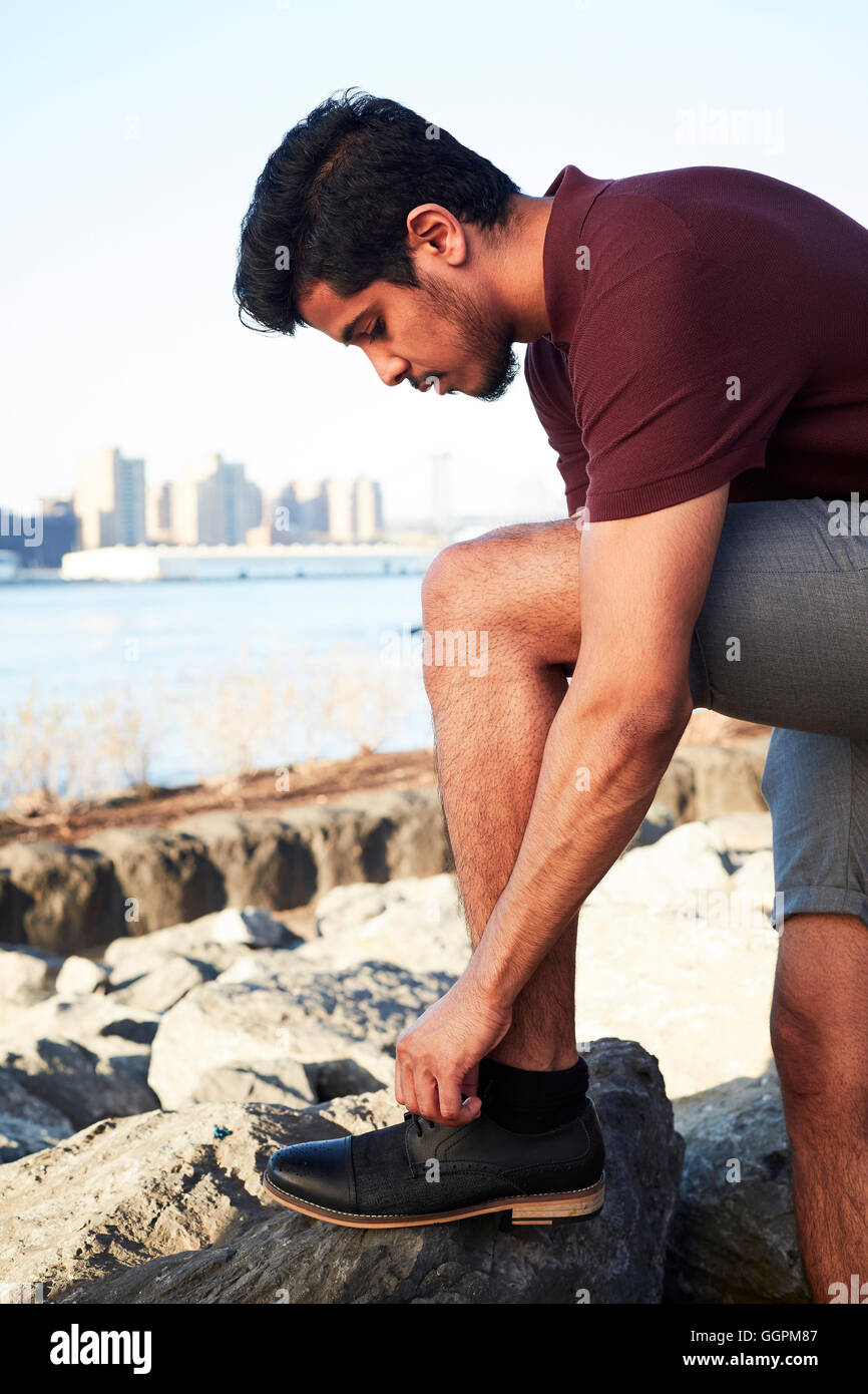 Middle Eastern man tying shoelace at waterfront Stock Photo