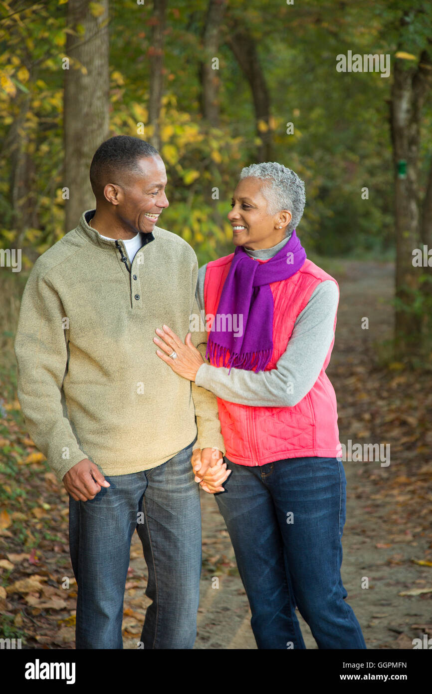 Older couple holding hands walking in forest Stock Photo
