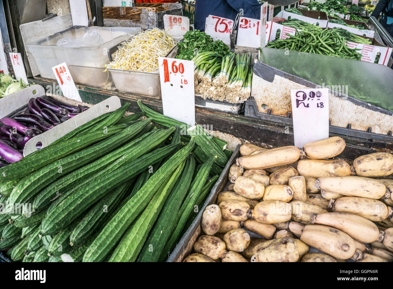 neatly arranged group of vegetables displayed inside & outside on sidewalk in front of Chinese greengrocer in New York Chinatown Stock Photo