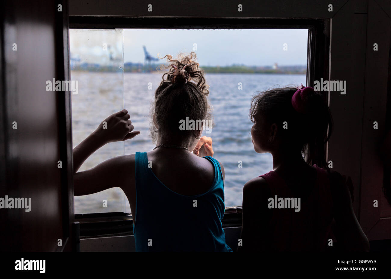 Two children looking out the window on a ferry boat. Havana, Cuba. Stock Photo