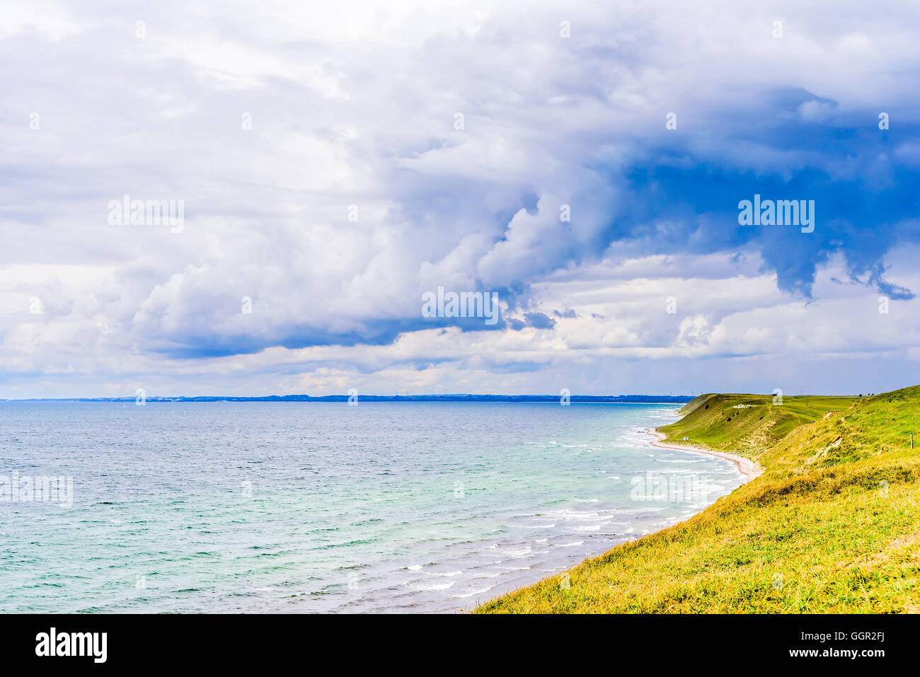 Storm clouds gather over the bay. Steep sandy hills with grass lead up to the grassland above. South coast of Skane, Sweden. Stock Photo