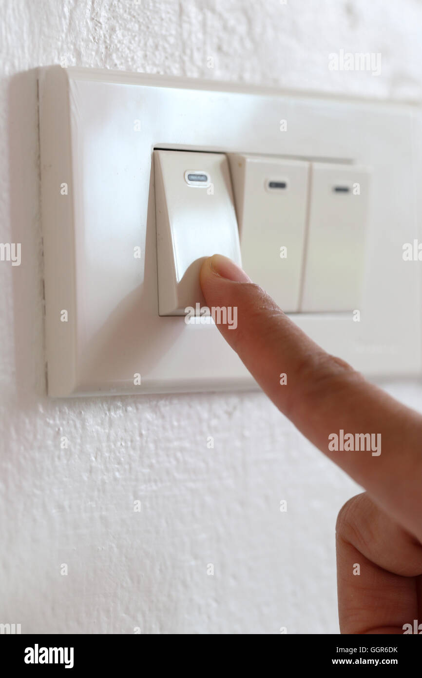 fingers are off light switch in the house,concept for energy saving reduce global warming. Stock Photo