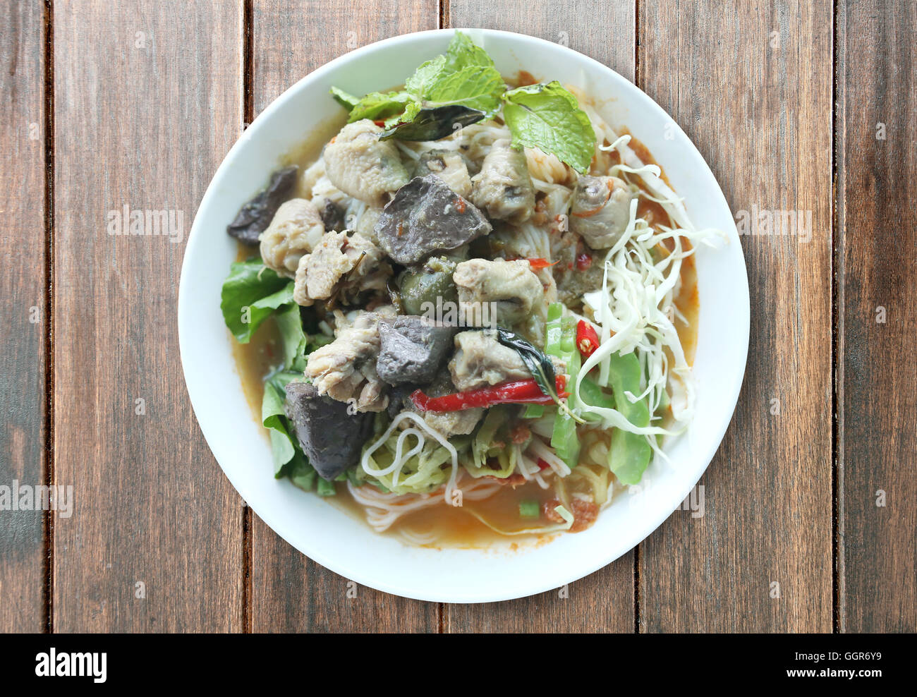 Curry chicken noodles (KHANOM CHIN) with vegetable,This is local Thai foods in Vermicelli rice on wooden background. Stock Photo