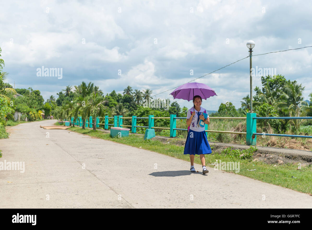 Young girl walking to school in uniform in the countryside of the Philippines Stock Photo