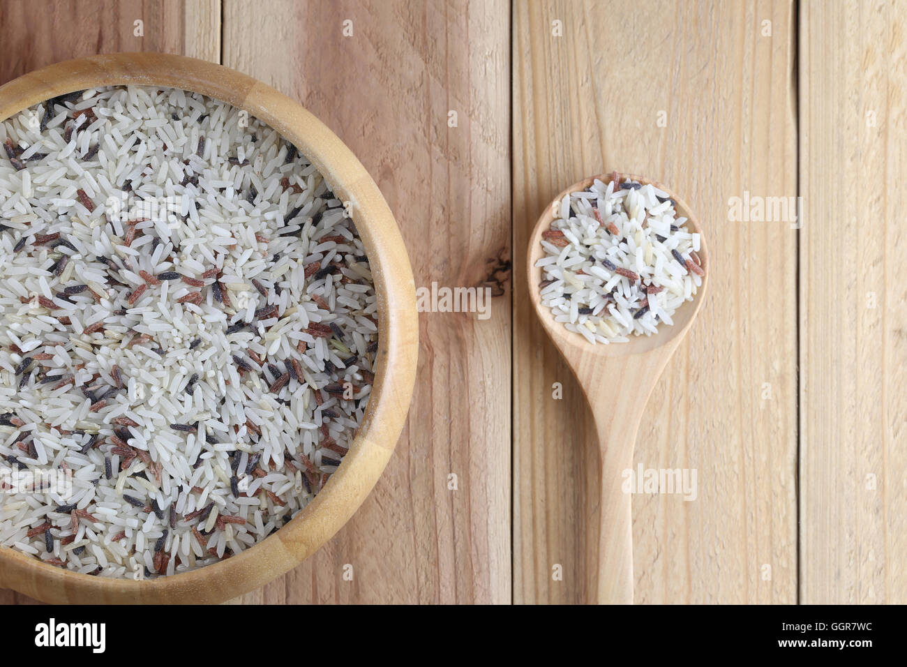 Organic rice in wooden spoon and bowl on wood background concept for nature food. Stock Photo