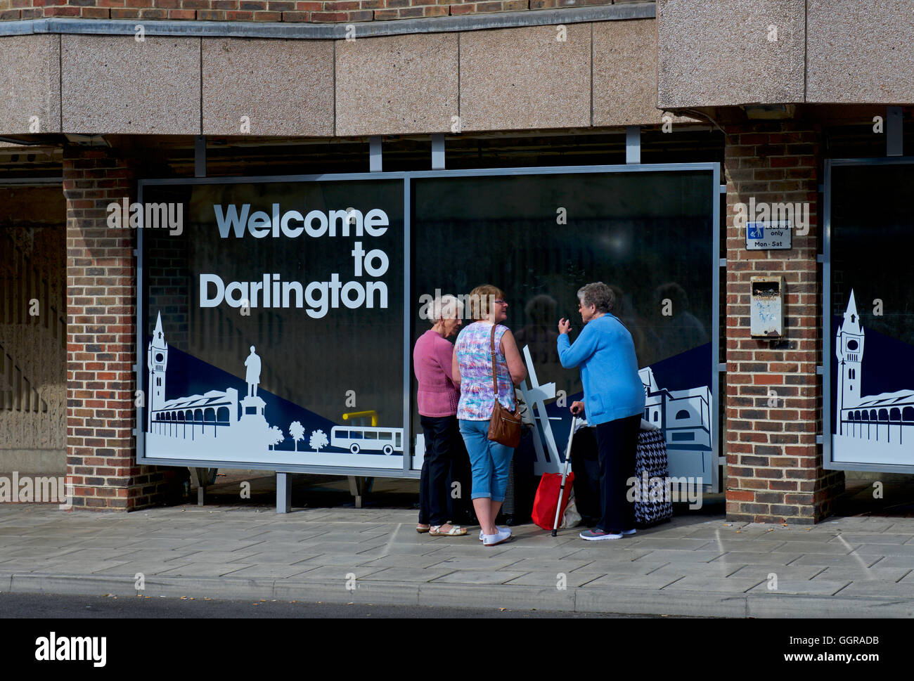 Three senior ladies chatting in front of sign - Welcome to Darlington - County Durham, England UK Stock Photo