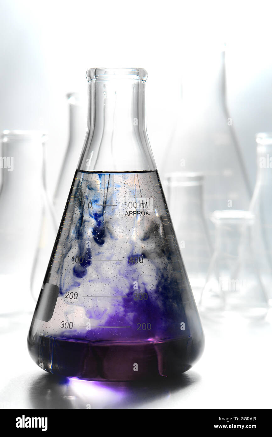 Scientific laboratory glass conical Erlenmeyer flask filled with swirling and reacting purple
