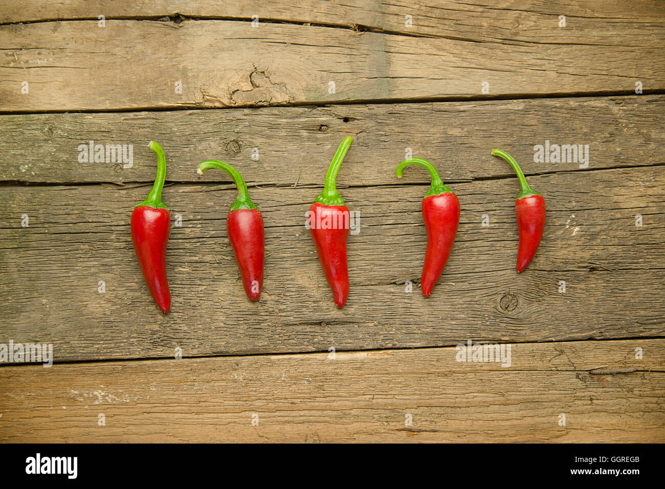 Red hot Chilli peppers on old wooden surface Stock Photo - Alamy
