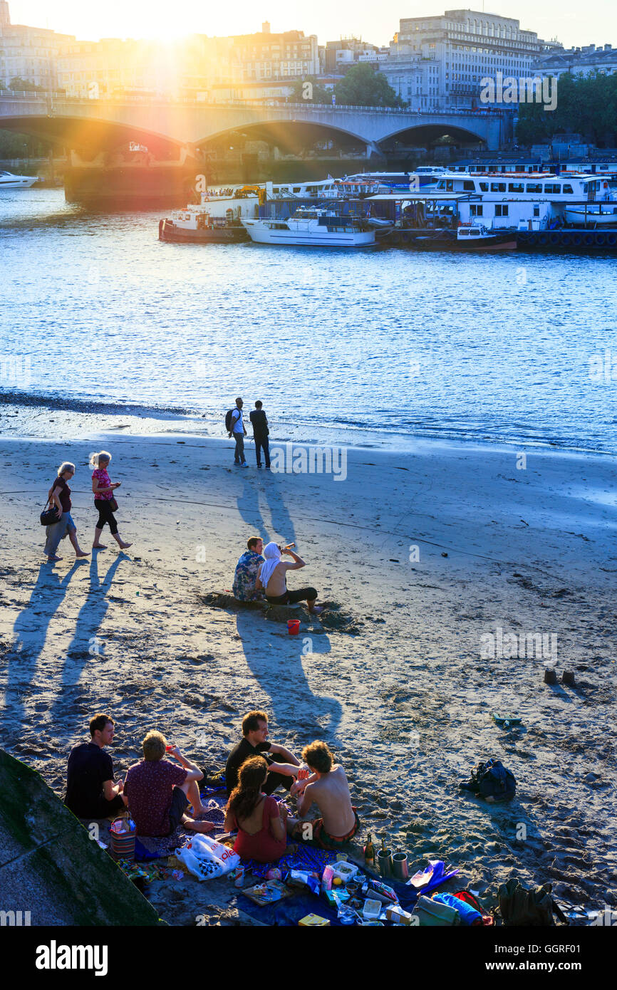 London, Waterloo. Locals on a River Thames beach in Summer with Waterloo Bridge in the background Stock Photo