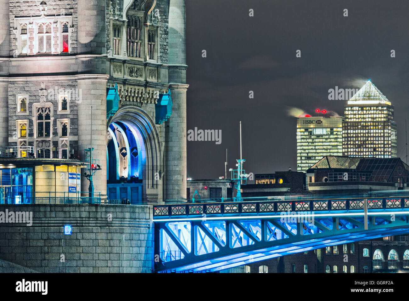 Detail of Tower Bridge, illuminated at night with the 1 Canada Square & 8 Canada Square (HSBC) buildings in the distance Stock Photo