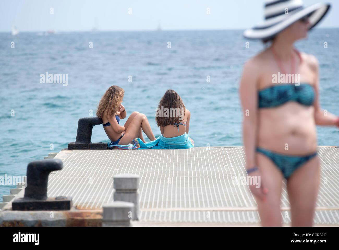 beach jetty sitting swimsuit women hat seaside Stock Photo