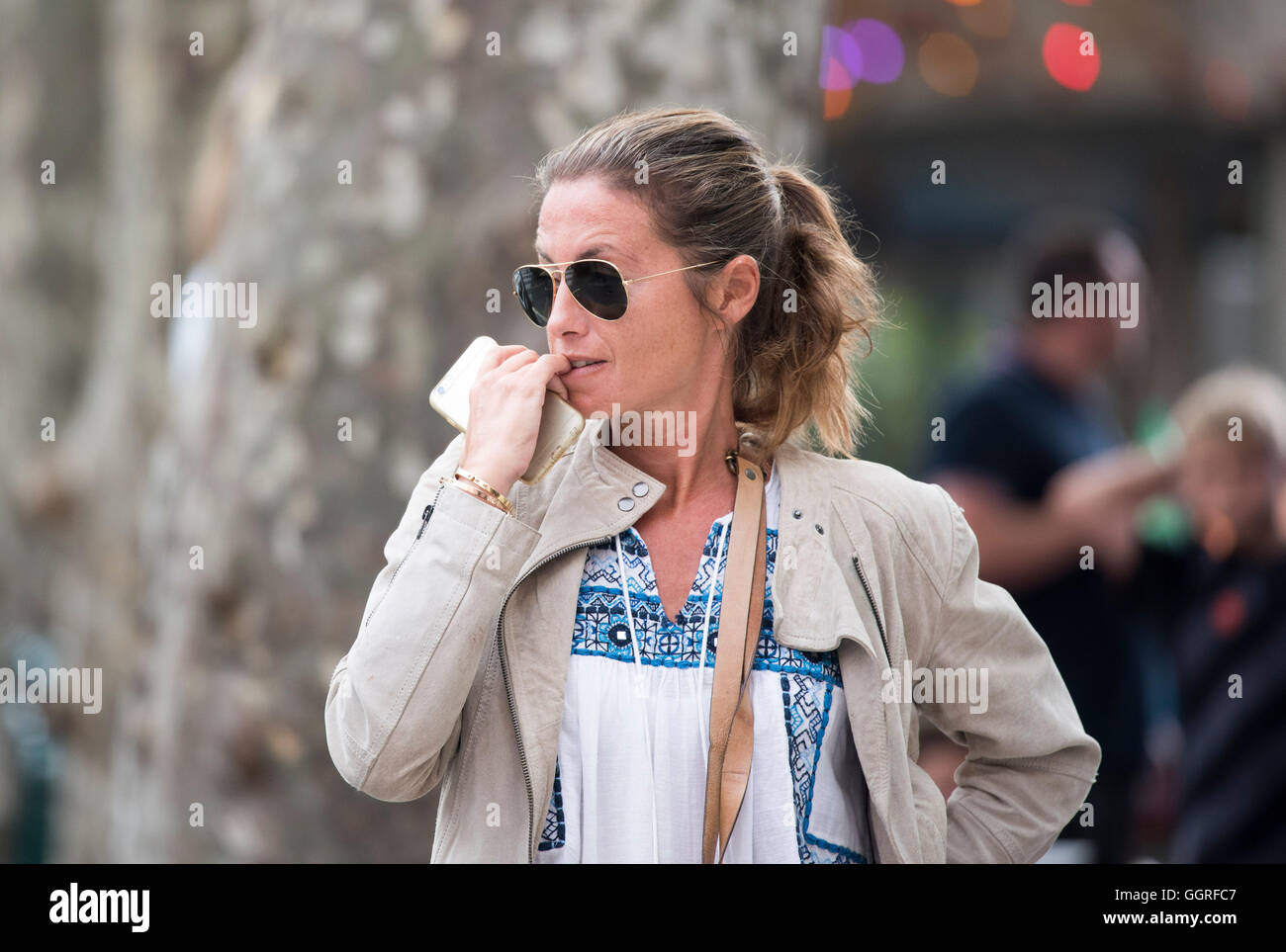 girl holding phone biting nails woman sunglasses Stock Photo