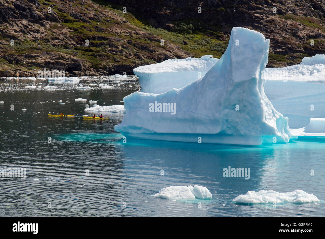 Tourists kayaking close to large Icebergs from Tunulliarfik fjord in summer. Narsaq, Kujalleq, Southern Greenland Stock Photo