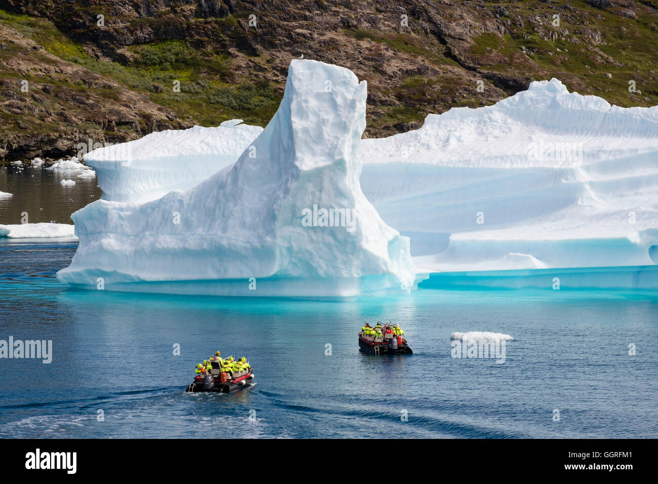 Tourists sailing in small boats on ocean sea close to large Icebergs from Tunulliarfik ice fjord in summer 2016. Narsaq, Southern Greenland Stock Photo