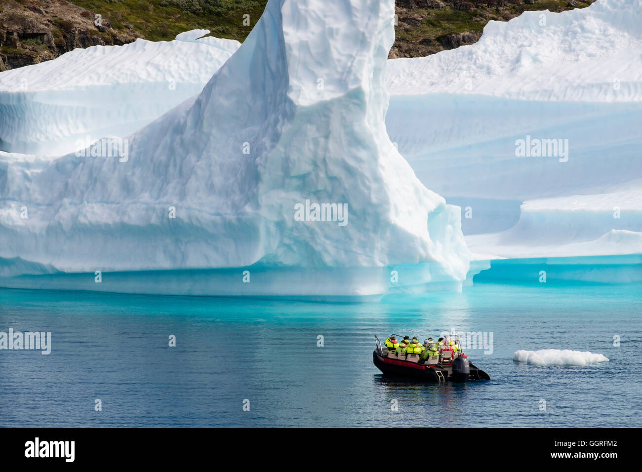 Tourists sailing in a small boat close to large Icebergs from Tunulliarfik ice fjord in summer. Narsaq, South Greenland Stock Photo