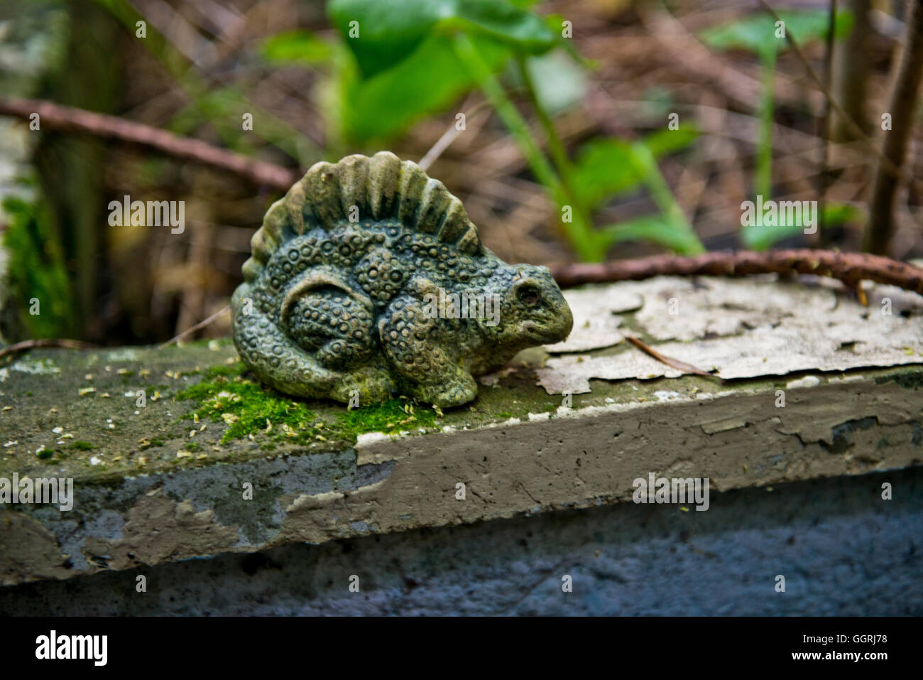 Small garden ornament of a Dinosaur found with the overgrown grounds of St Clements Hospital, East End of London. Stock Photo