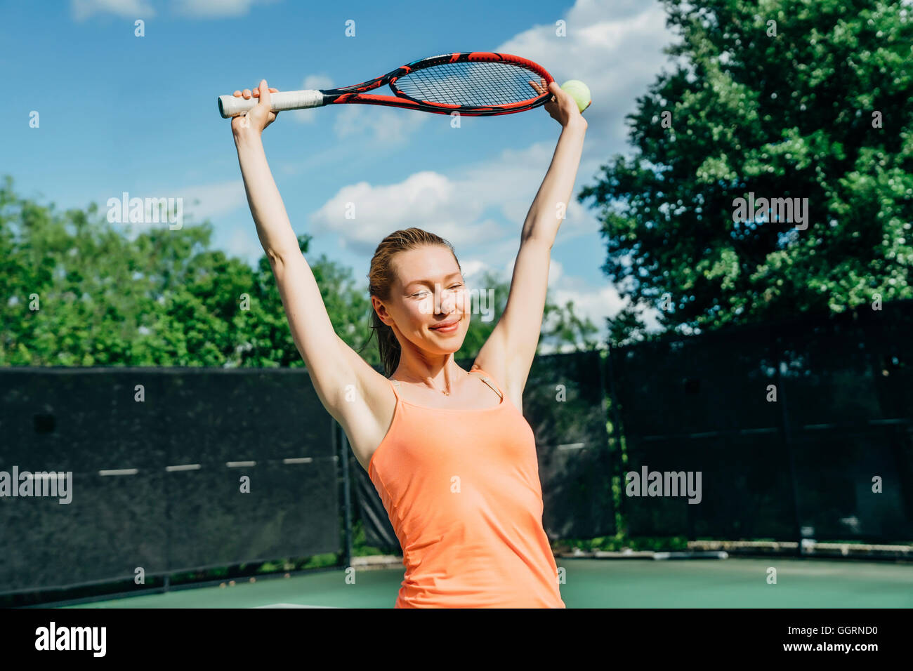 Caucasian woman stretching arms on tennis court Stock Photo