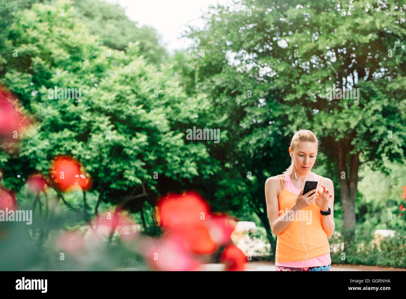 Caucasian woman using cell phone and earbuds outdoors Stock Photo