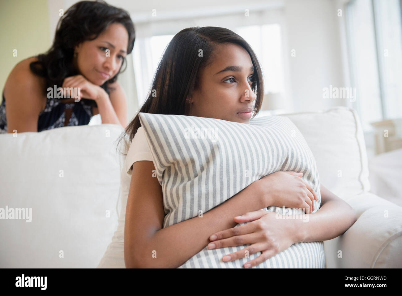 Mother watching pensive daughter clutching pillow Stock Photo