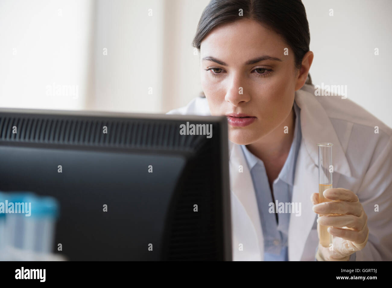 Caucasian scientist holding vial using computer Stock Photo Alamy