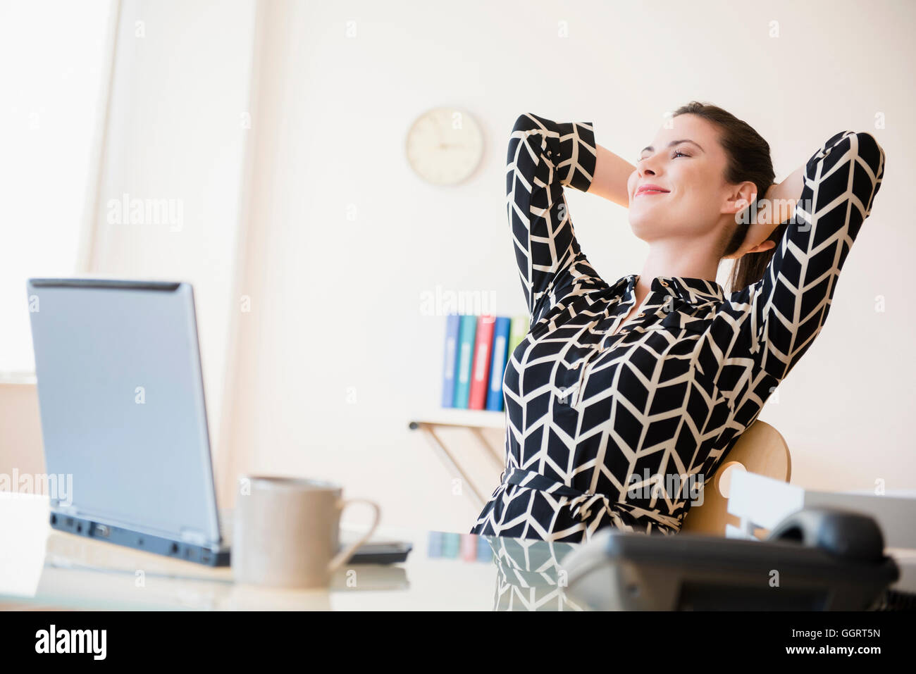 Satisfied Caucasian businesswoman relaxing in office Stock Photo