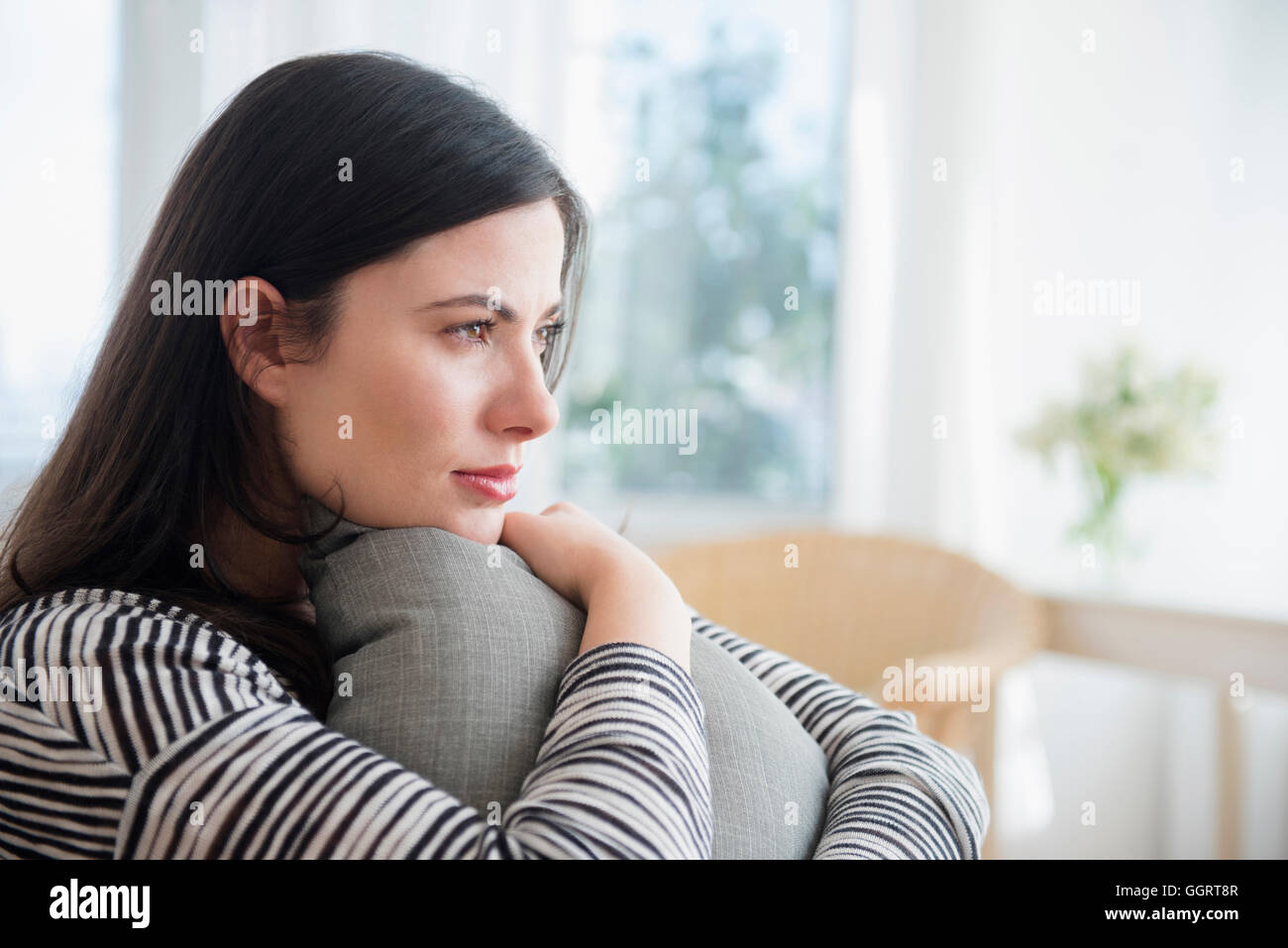 Pensive Caucasian woman clutching pillow Stock Photo