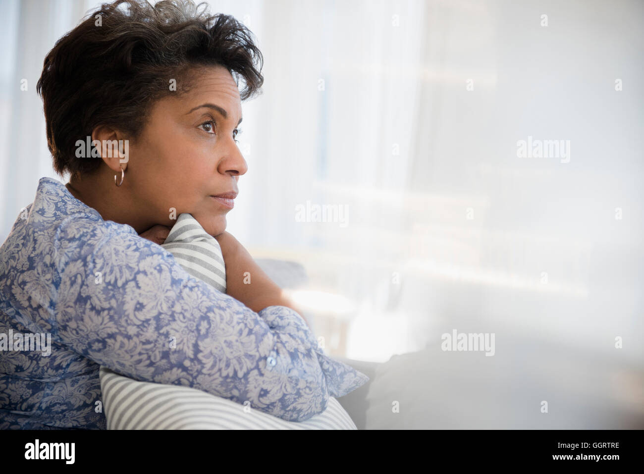 Pensive older Black woman clutching pillow Stock Photo