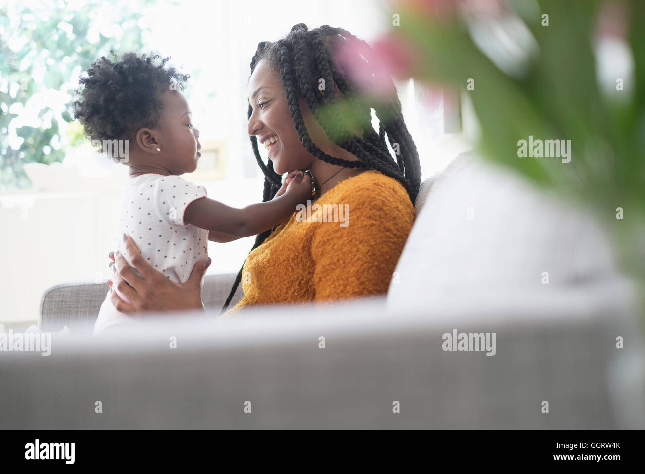 Black woman playing with baby daughter on sofa Stock Photo