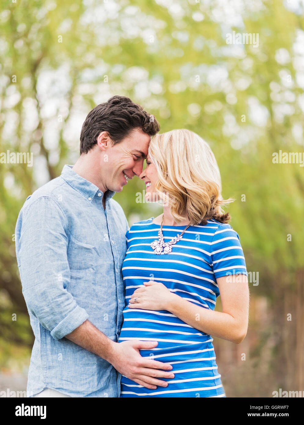 Smiling Caucasian man and expectant mother rubbing noses Stock Photo