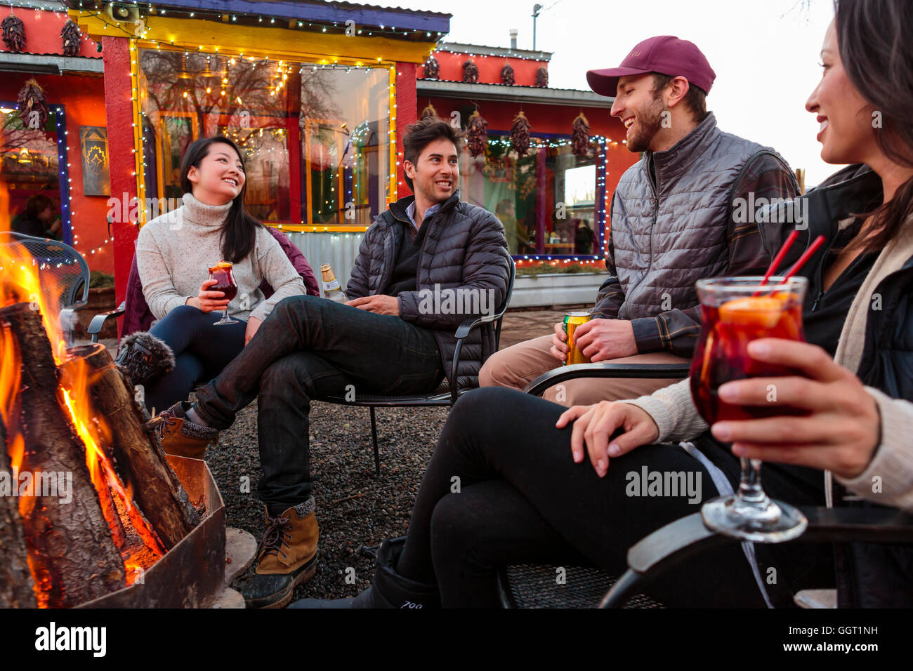 Couples drinking cocktails and beer outdoors at storefront campfire Stock Photo