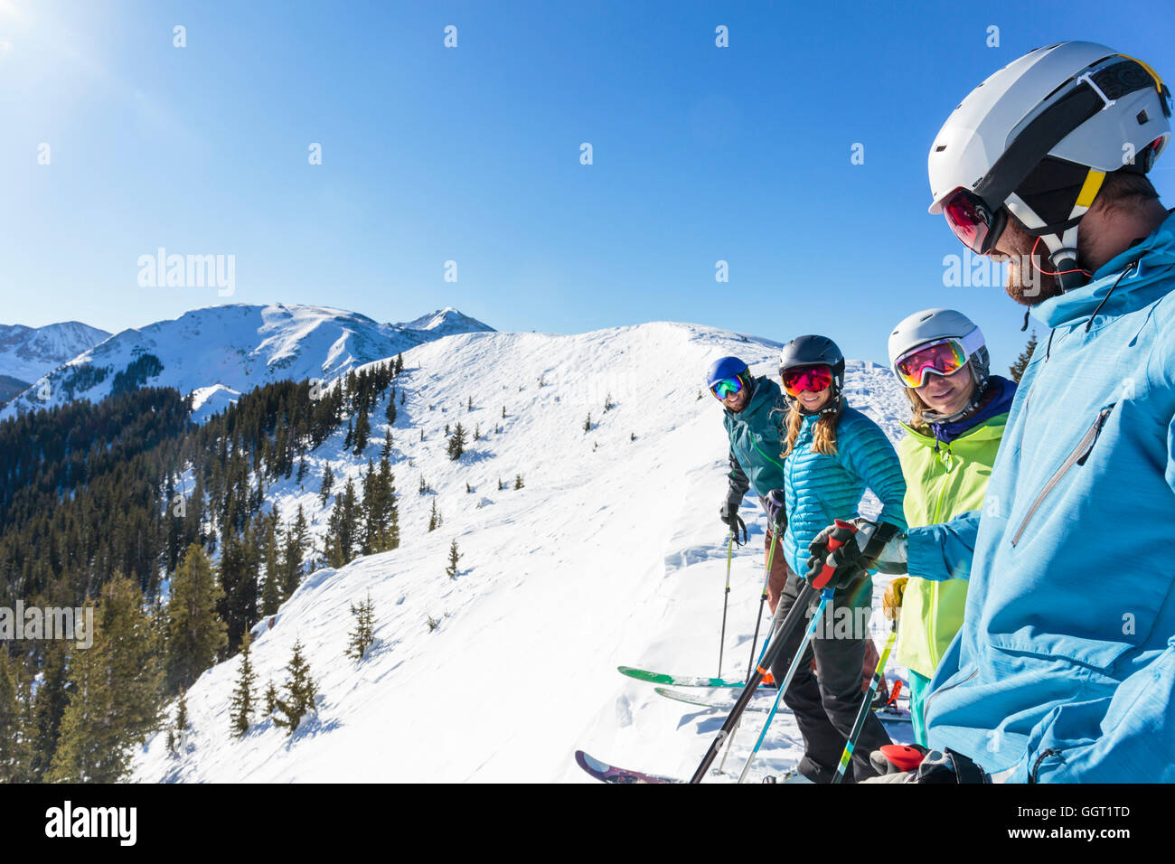 Friends on skis standing on snowy mountaintop Stock Photo