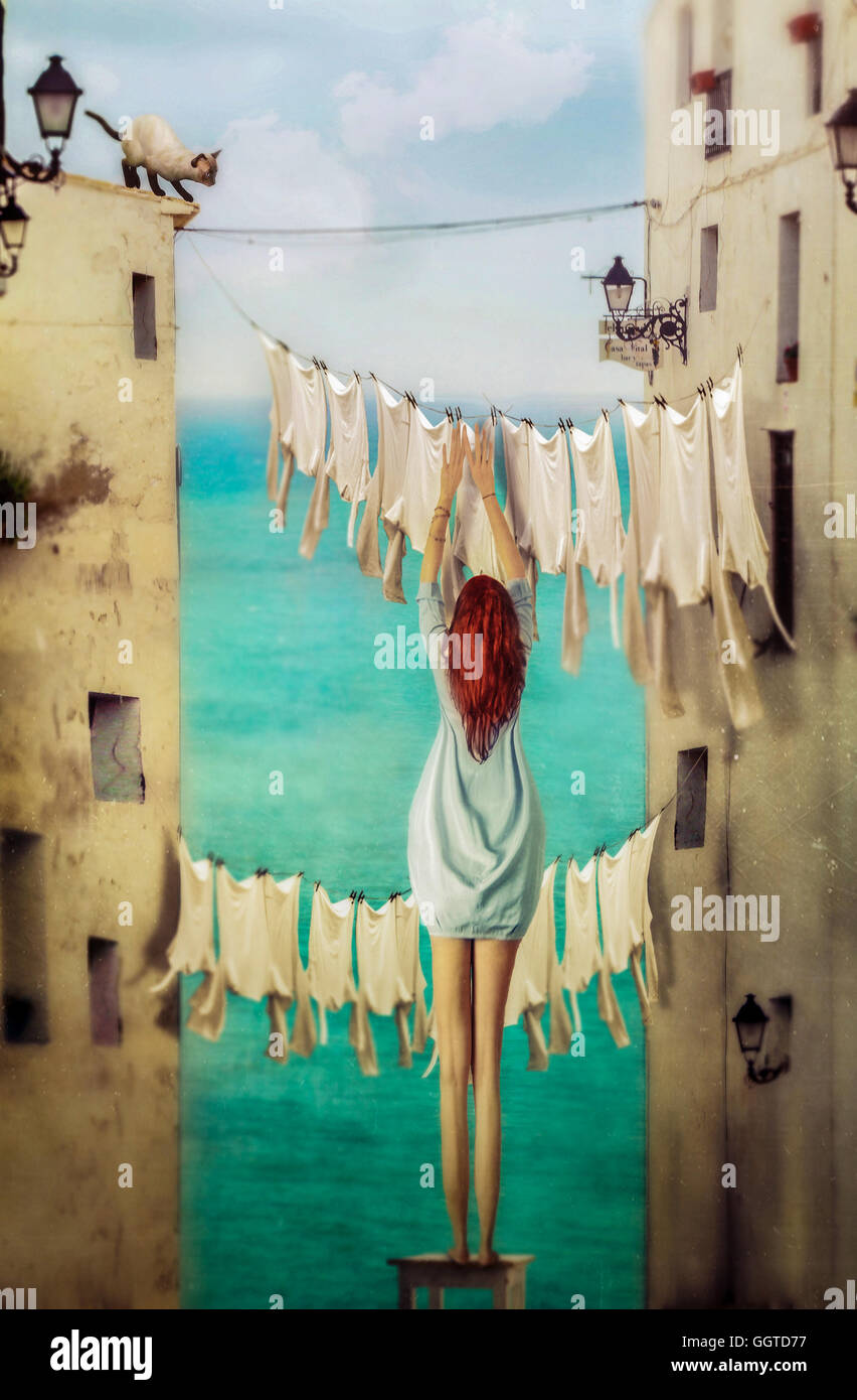 surreal image of back of young girl with long legs hanging clothes on washing line Stock Photo
