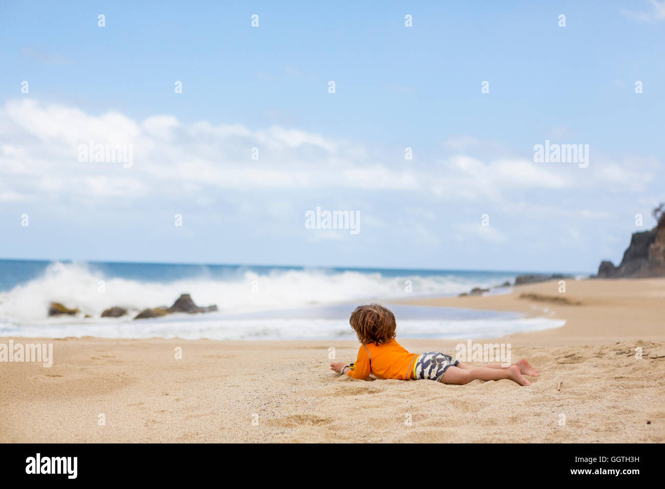 Caucasian boy laying on beach Stock Photo