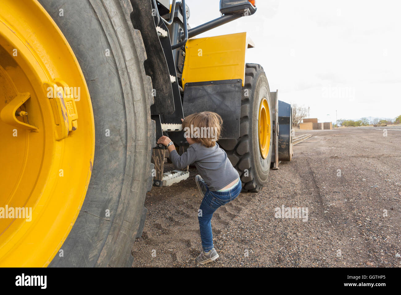 Caucasian boy climbing ladder on tractor Stock Photo