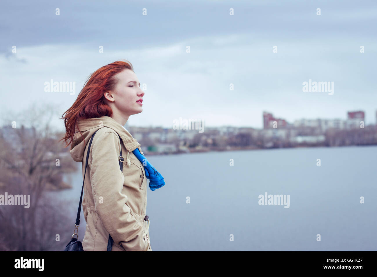 Woman with red hair standing at waterfront Stock Photo