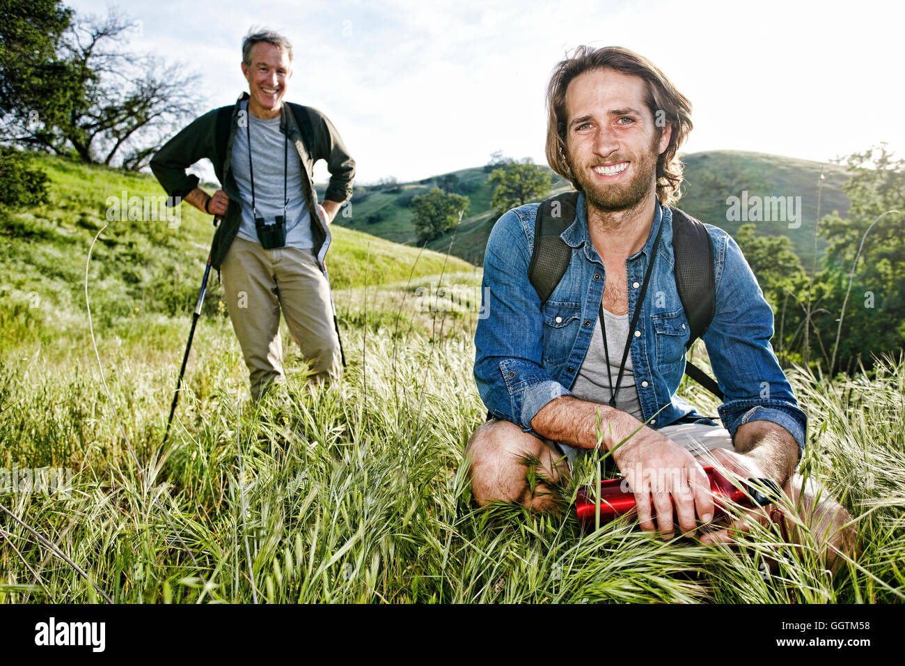 Caucasian hikers resting in grass on mountain Stock Photo