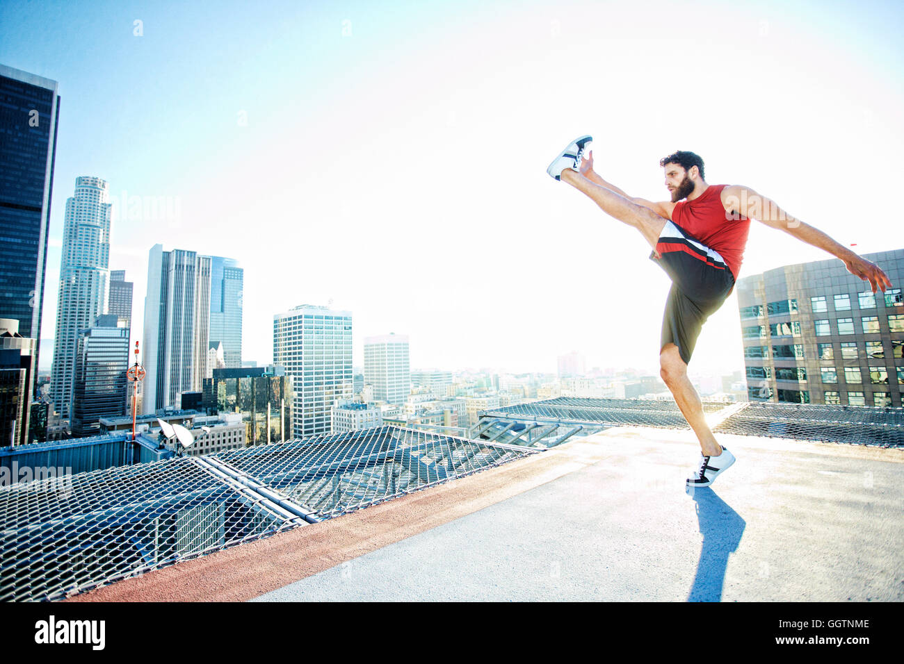 Caucasian man kicking on urban rooftop Stock Photo