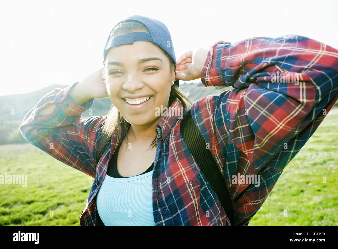 Smiling Mixed Race woman backpacking in field Stock Photo