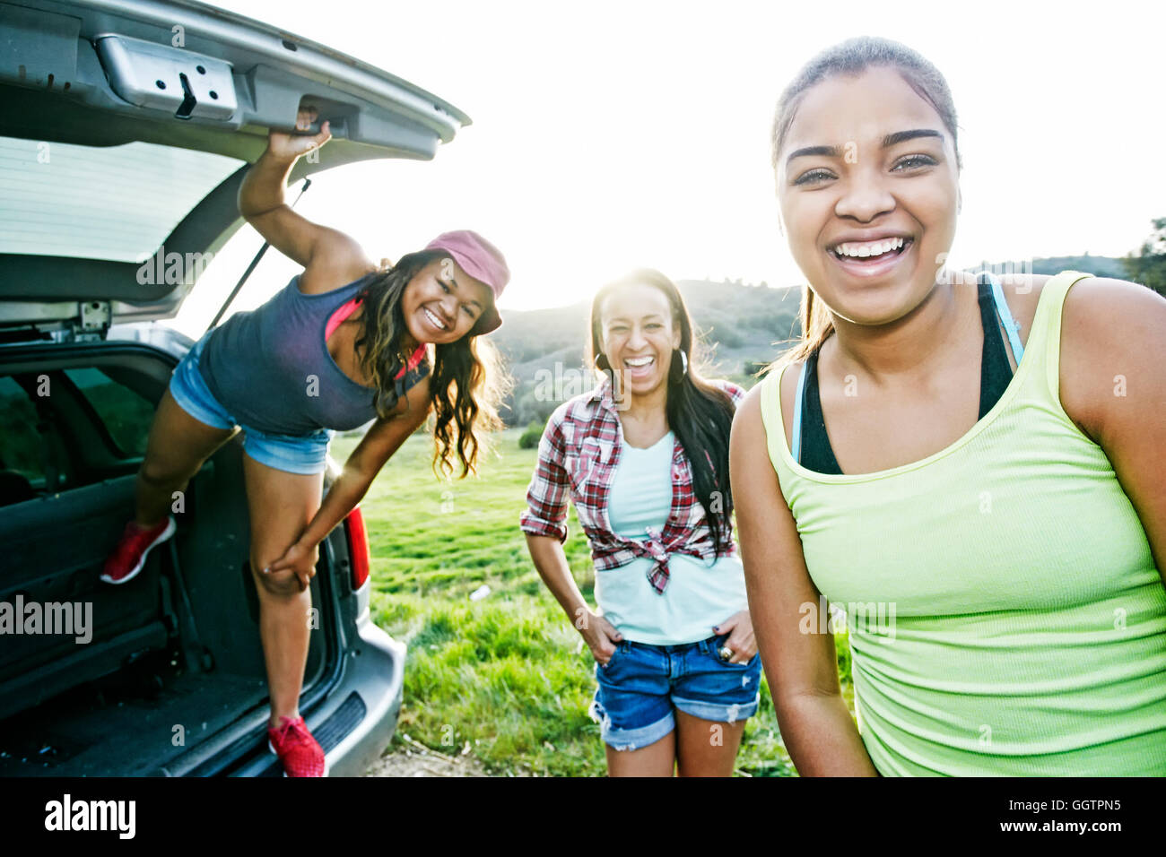 Mixed Race mother and daughters at hatch of car laughing Stock Photo