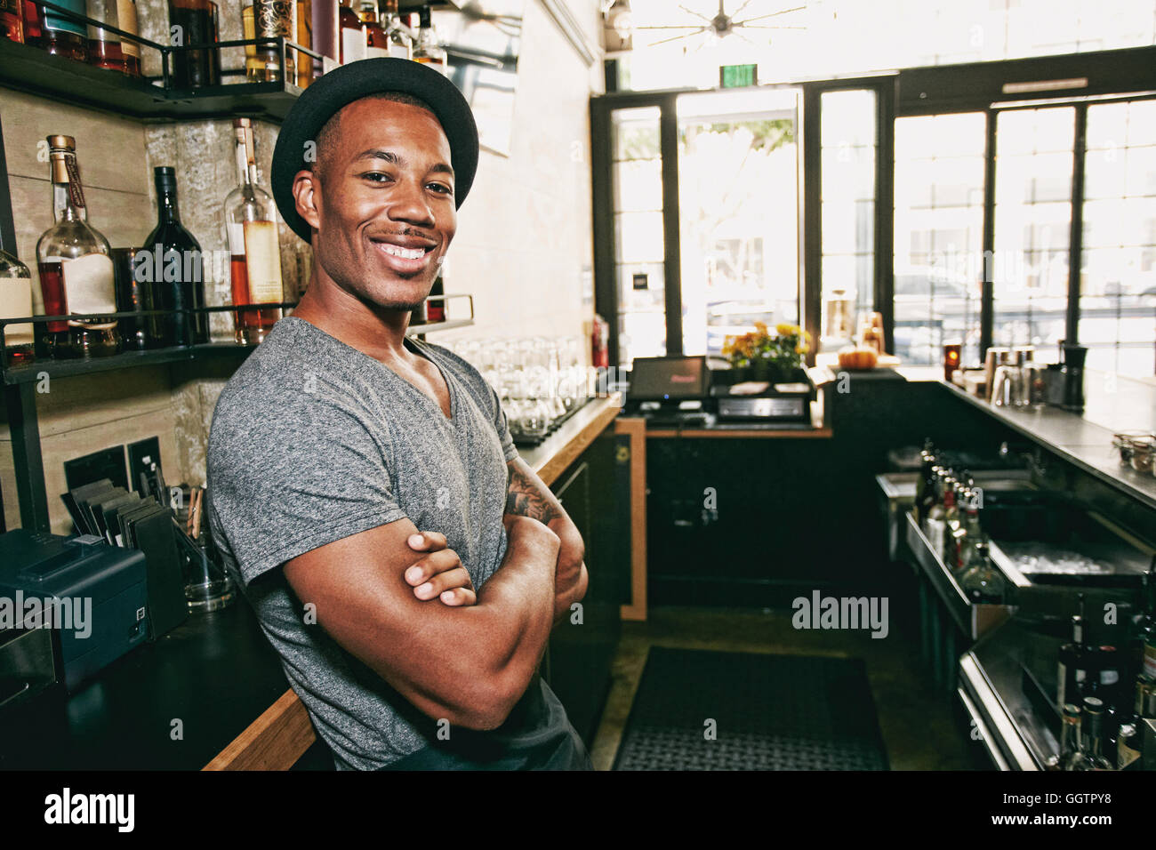 Smiling Black bartender relaxing behind bar Stock Photo