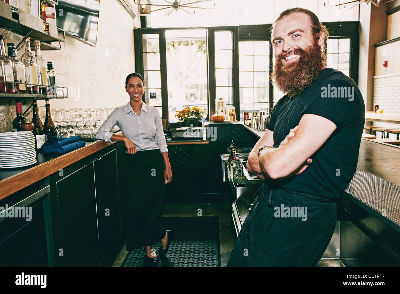 Smiling bartenders relaxing behind bar Stock Photo