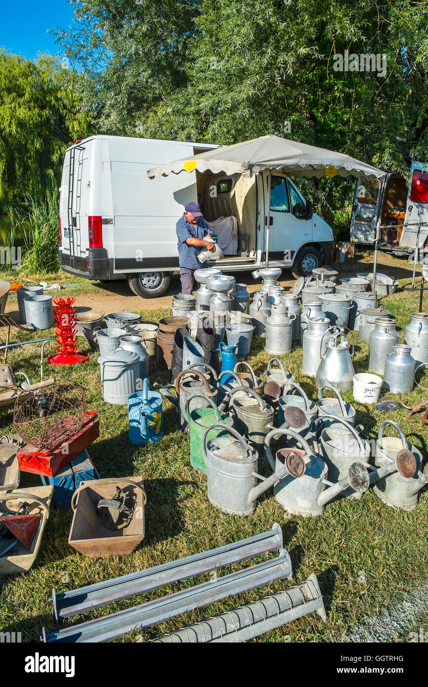 Stall-holder selling old watering cans and milk churns at open-air event - sud-Touraine, France. Stock Photo