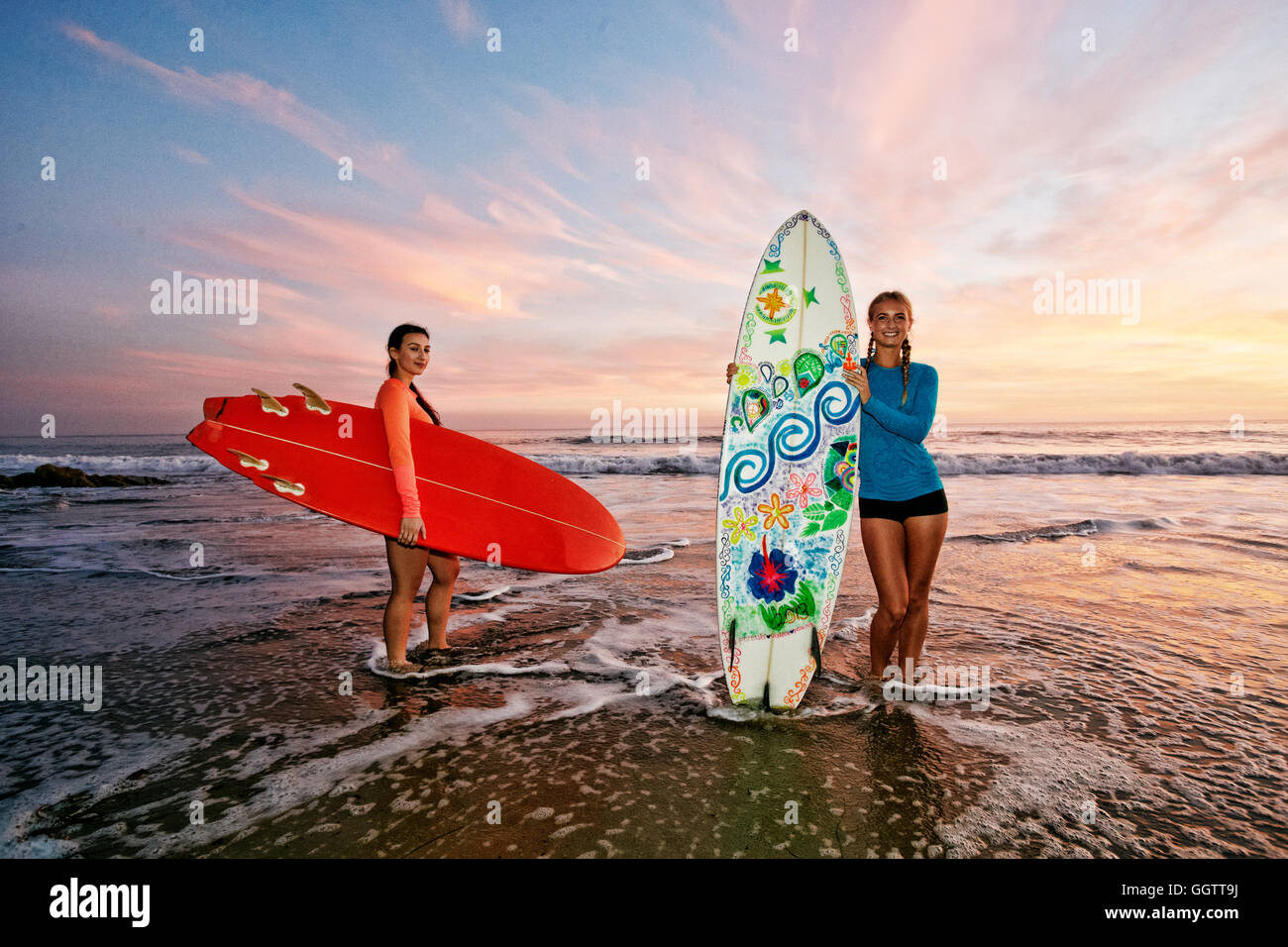 Women standing in ocean waves holding surfboards at beach Stock Photo